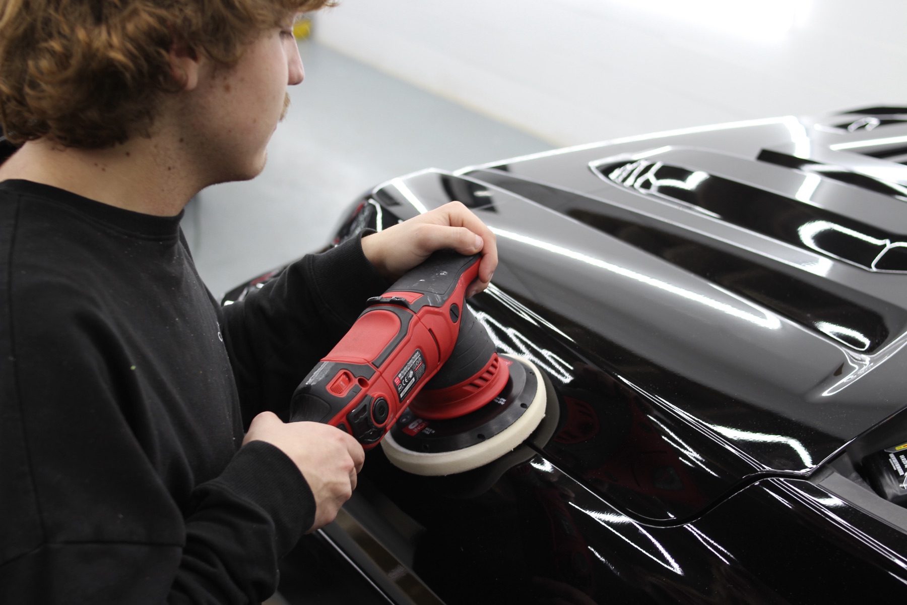 Machine polishing a black hood at QMD